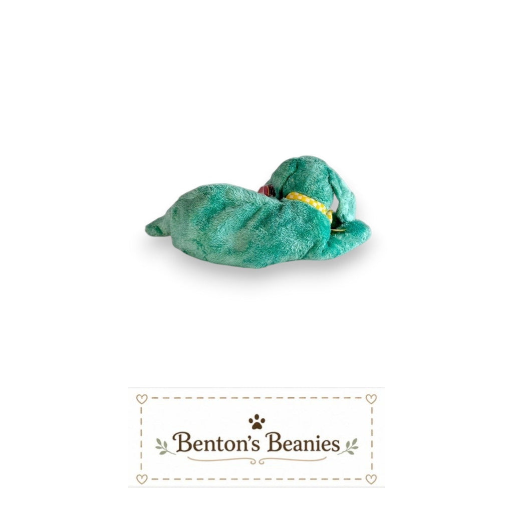 The Beanie Center Diddley the Dog, a turquoise plush toy with floppy ears and a yellow checkered collar, lounging relaxed.