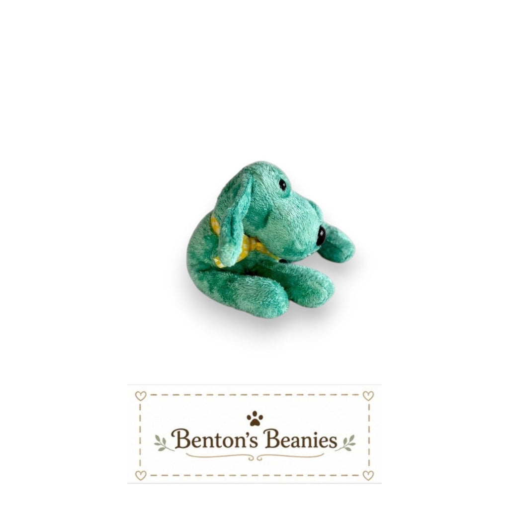 The Beanie Center Diddley the Dog, a turquoise plush toy with floppy ears and a yellow checkered bow tie, lying down.